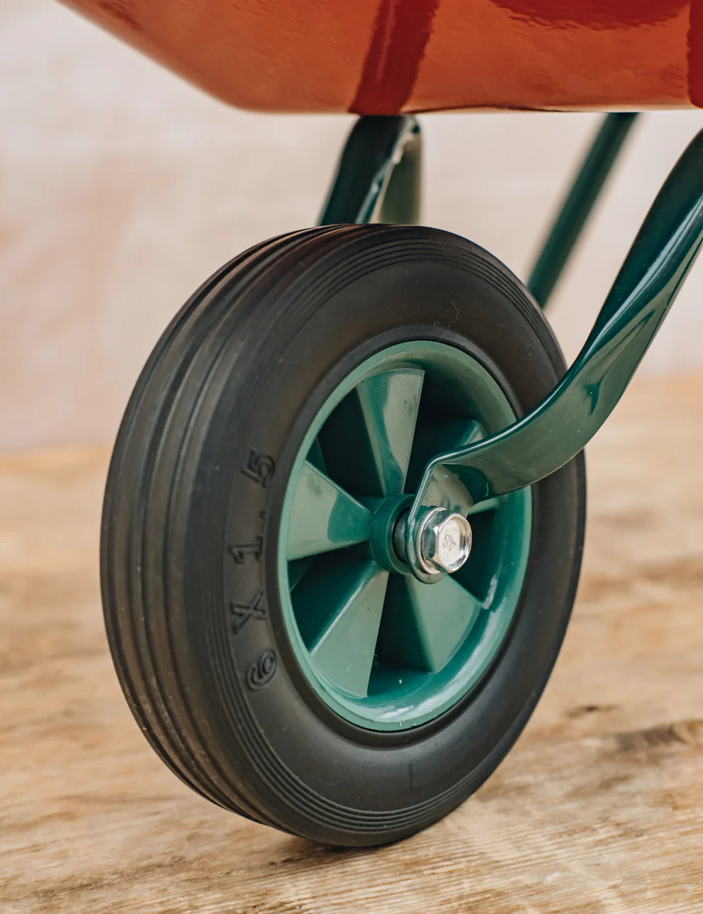 Close-up of a wheel with a green rim and black tire on a wooden surface.