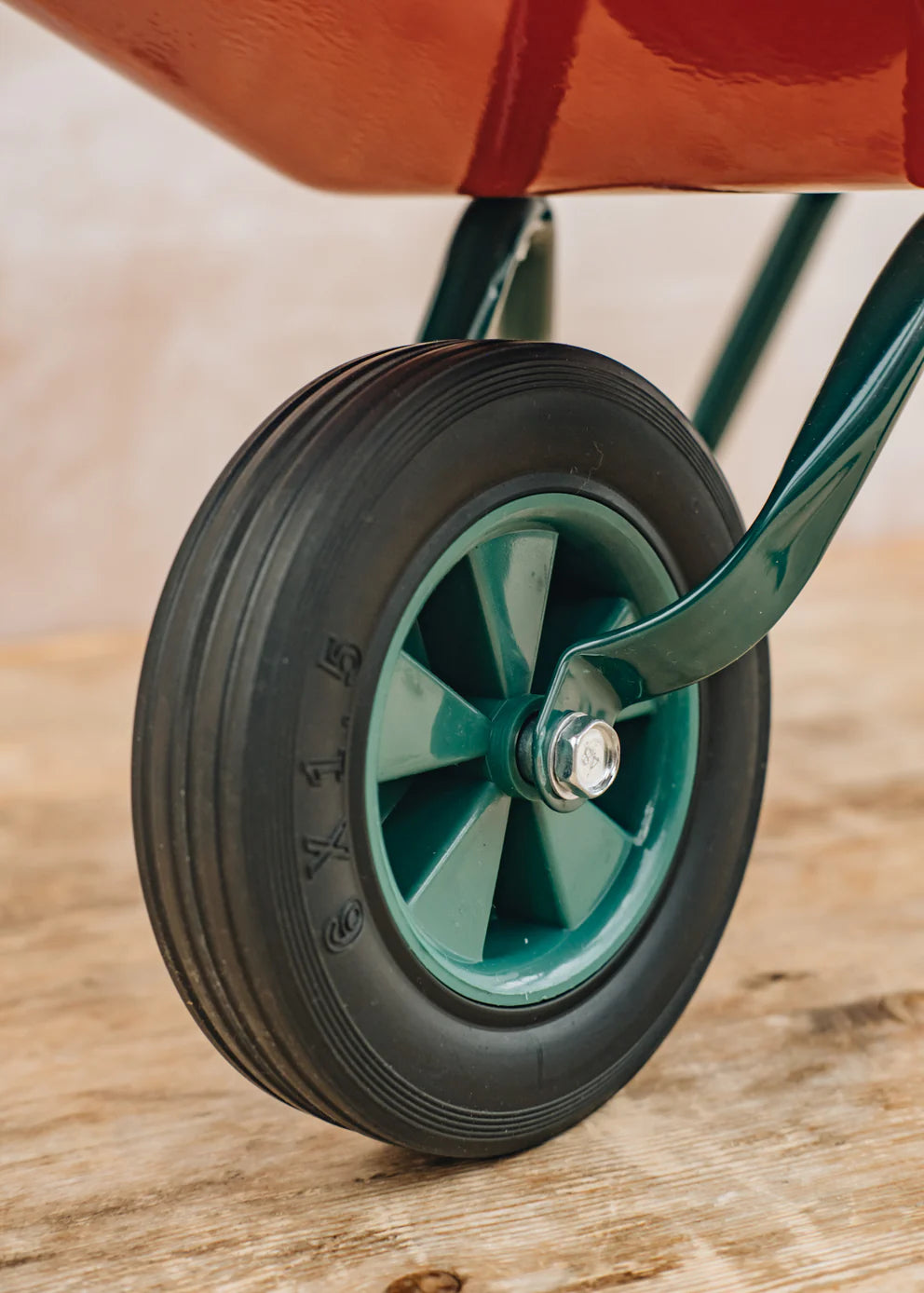 Close-up of a wheel with a green rim and black tire on a wooden surface.