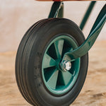 Close-up of a wheel with a green rim and black tire on a wooden surface.